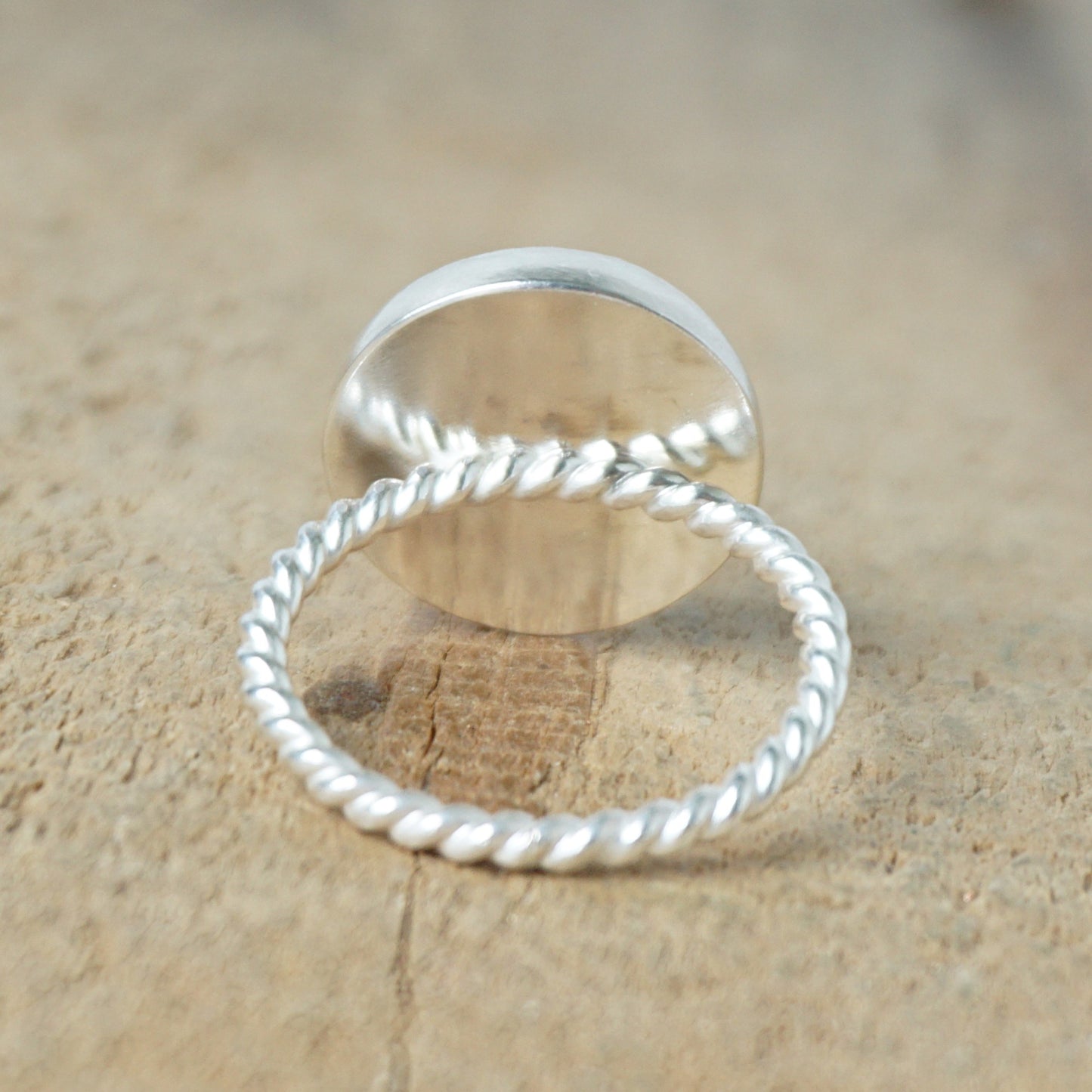 back view of a silver ring with a blue stone on a wooden background