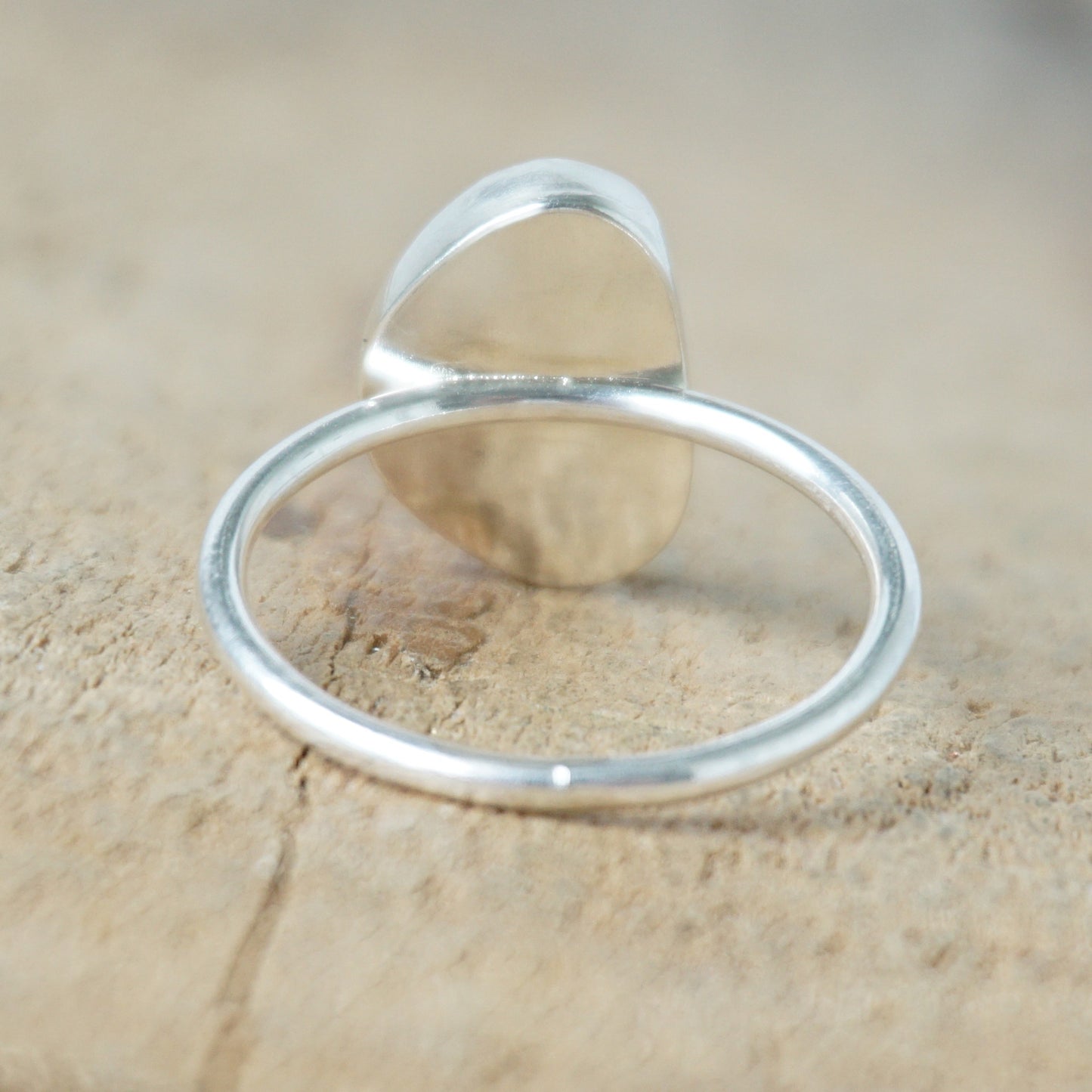 back view of a Turquoise ring with silver band on a wooden surface