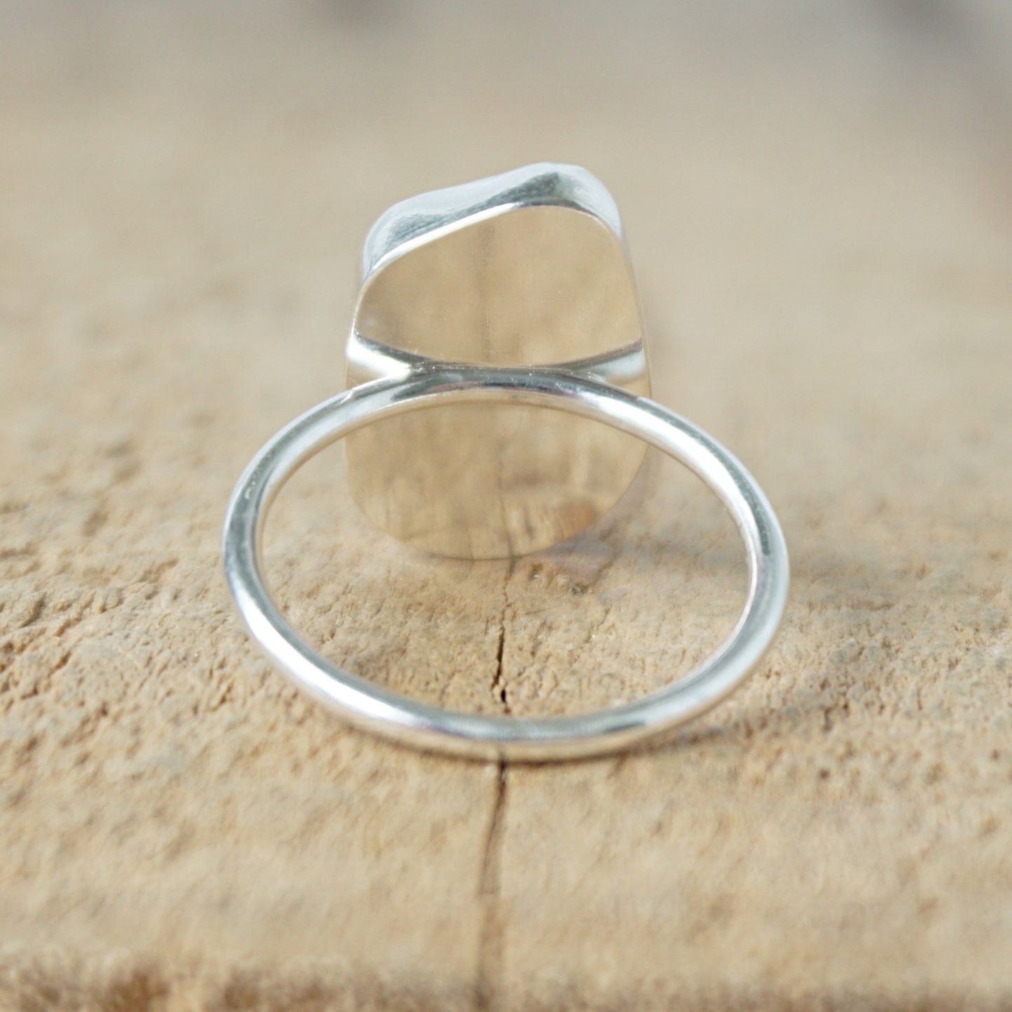back view of a silver ring with cobalt blue sea glass, on a wooden surface.
