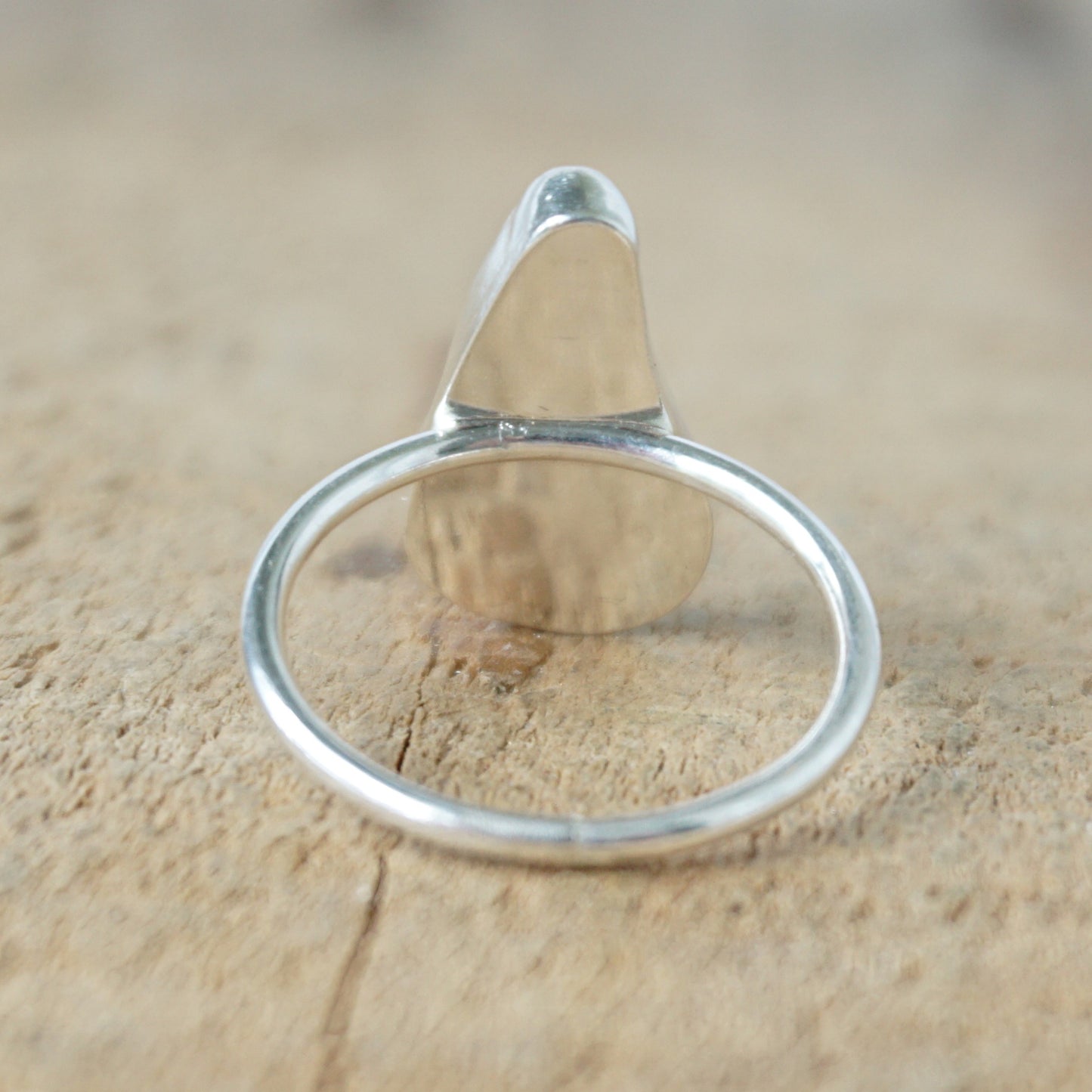 back view of a silver ring with kelly green sea glass, on a wooden surface.