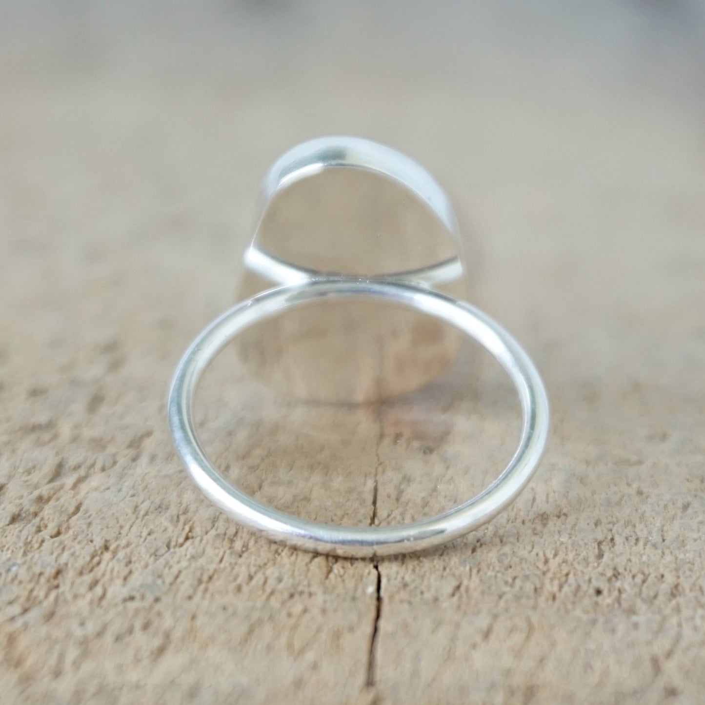back view of a silver ring with seafoam green sea glass, on a wooden surface.