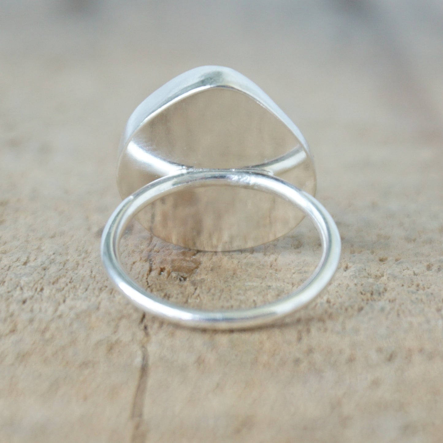 back view of a silver ring with seafoam green sea glass, on a wooden surface.