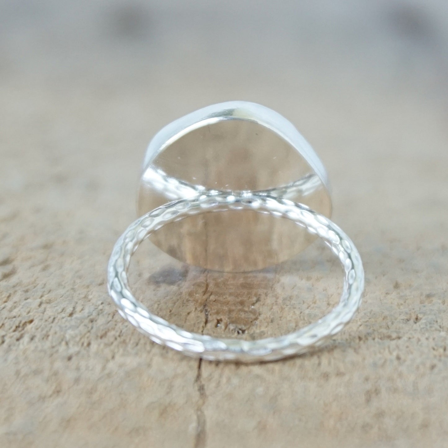 back view of a silver ring with seafoam green sea glass, on a wooden surface.