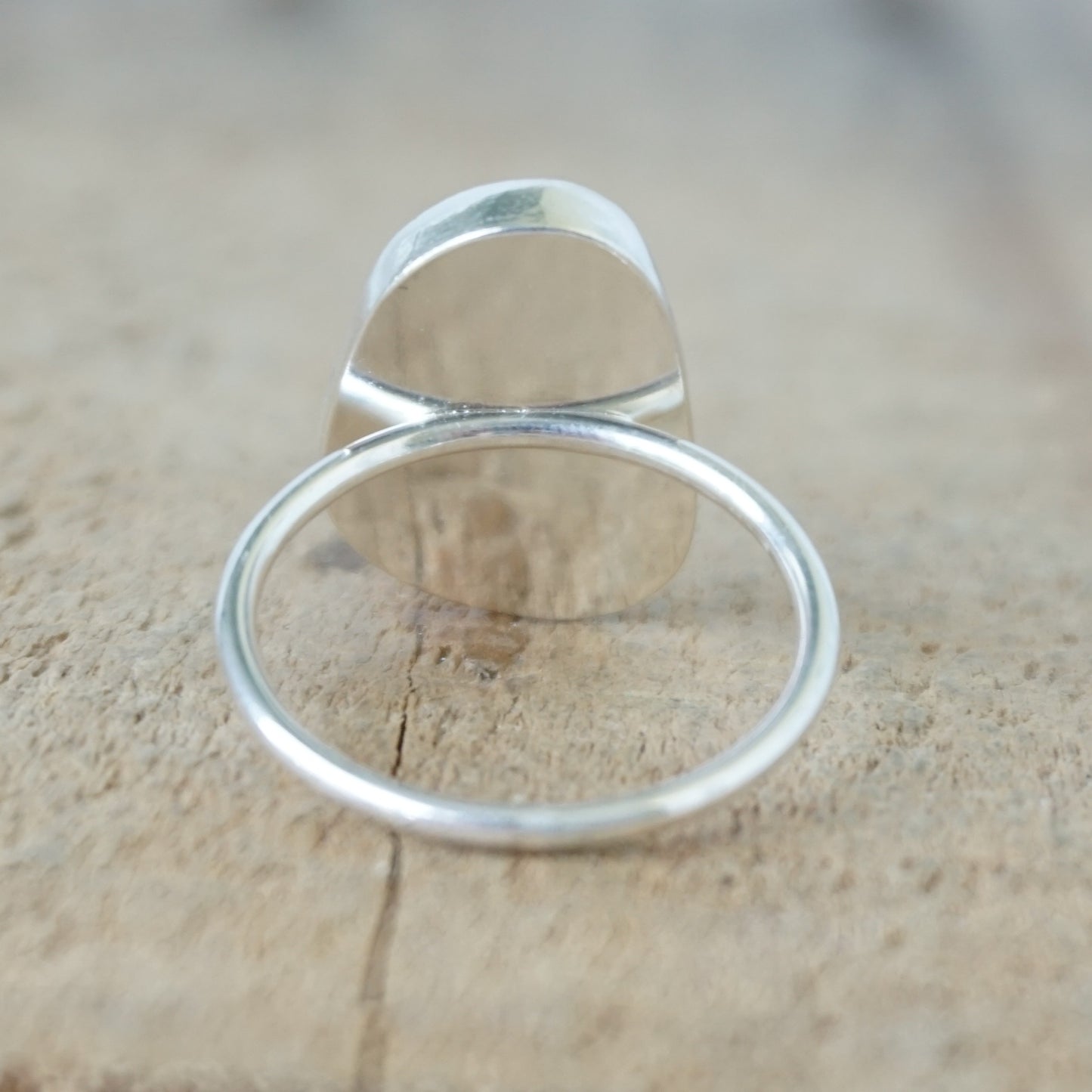 back view of a silver ring with seafoam green sea glass, on a wooden surface.