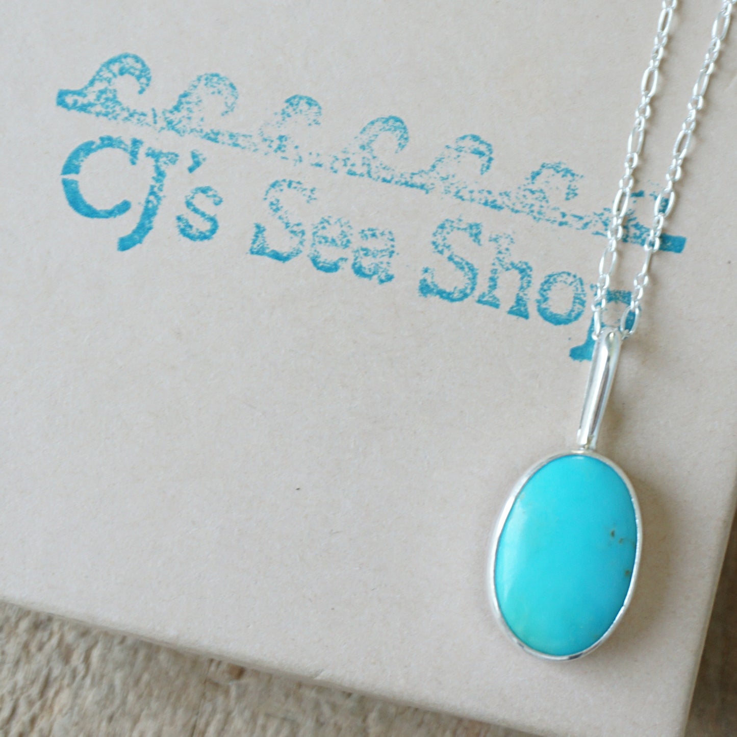 sterling silver pendant with turquoise stone, displayed on a gift box