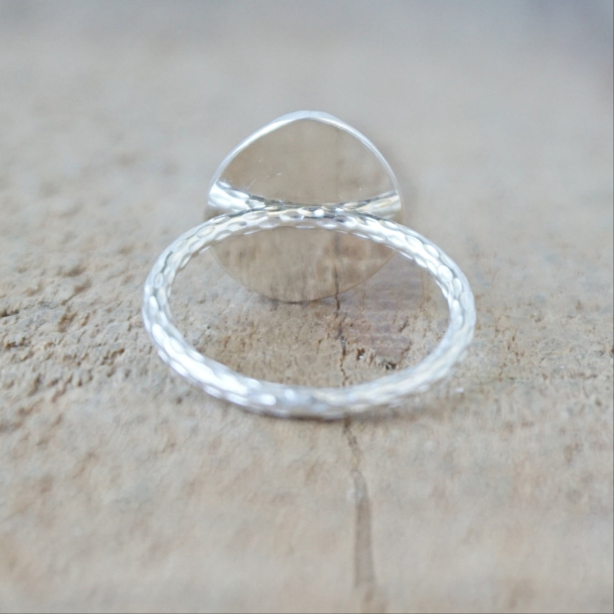 back view of a silver ring with a turquoise ring, against a wooden background