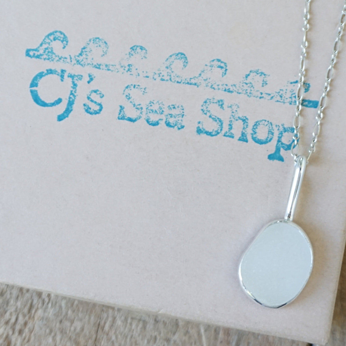 silver pendant with frosted clear sea glass, displayed on a gift box