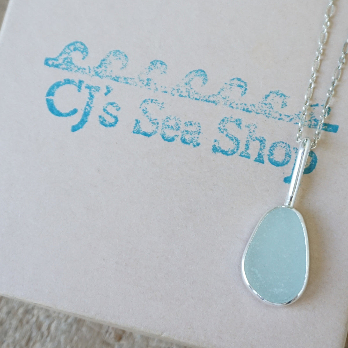 silver pendant with seafoam green sea glass, displayed on a gift box