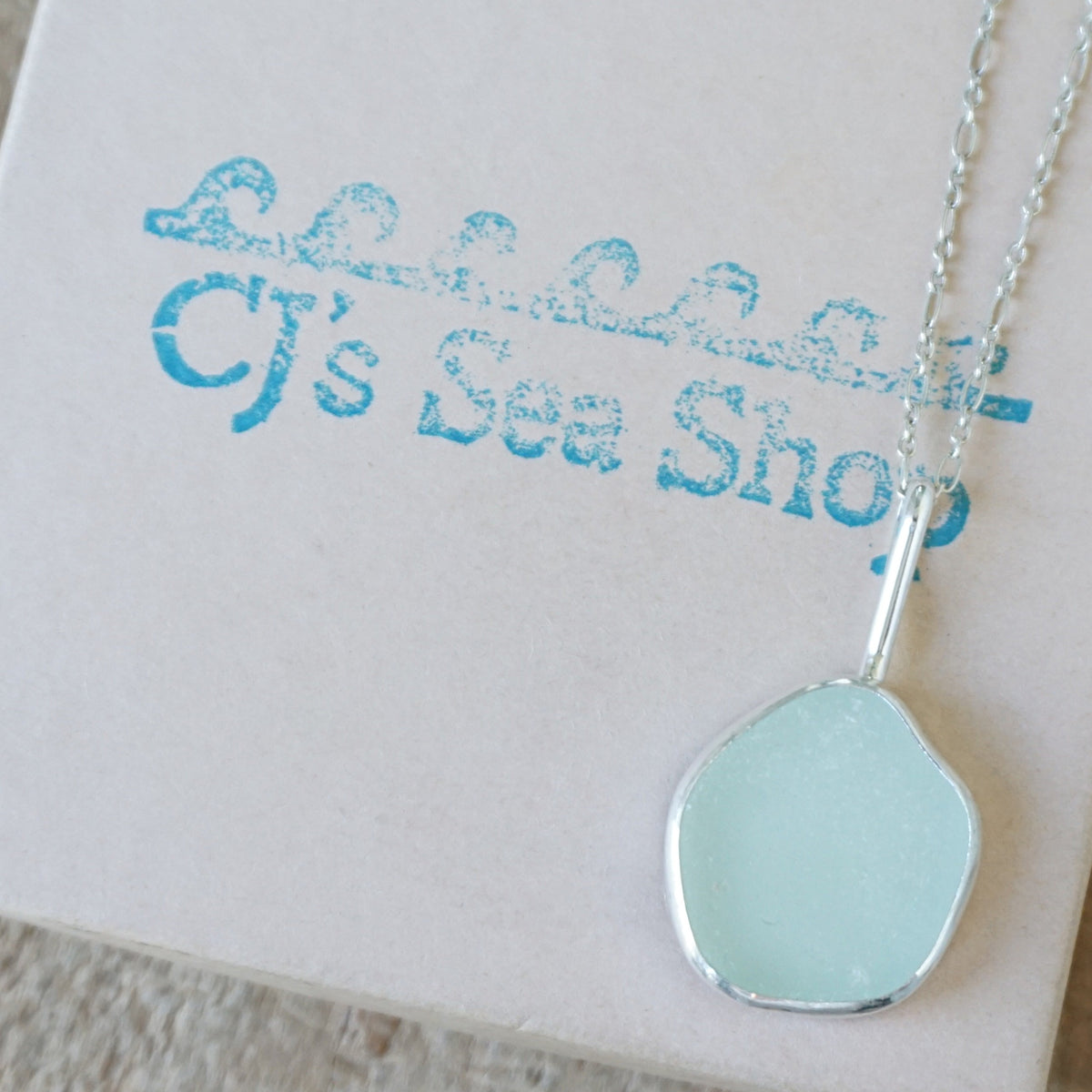 silver pendant with seafoam green sea glass, displayed on a gift box