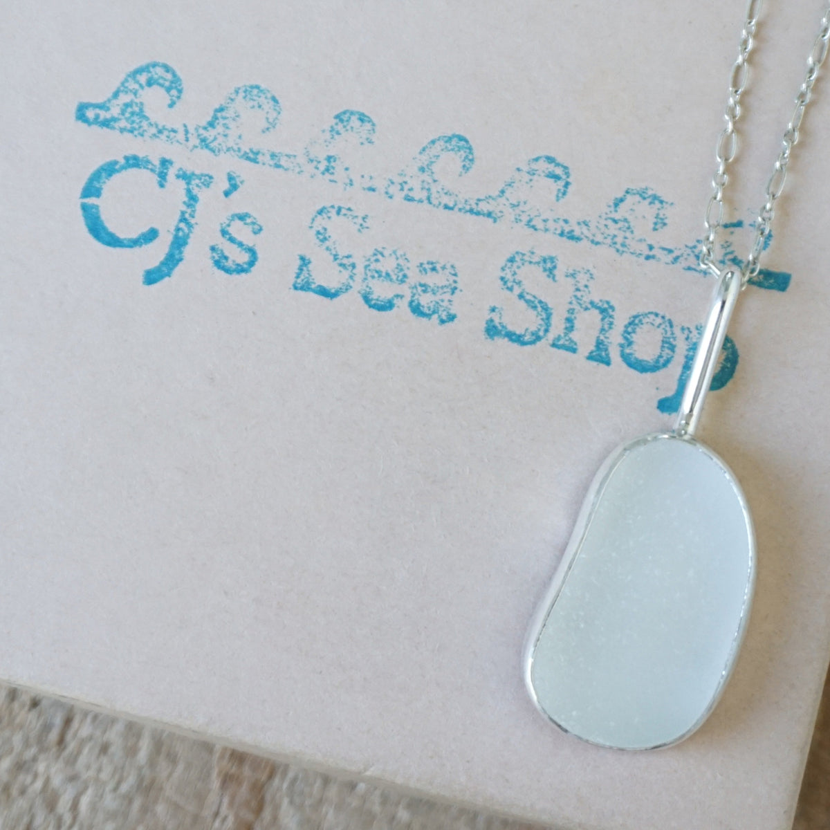 silver pendant with frosted clear sea glass, displayed on a gift box