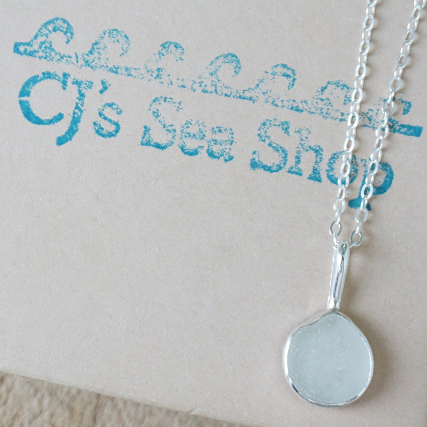 frosted clear sea glass and silver pendant, on a gift box