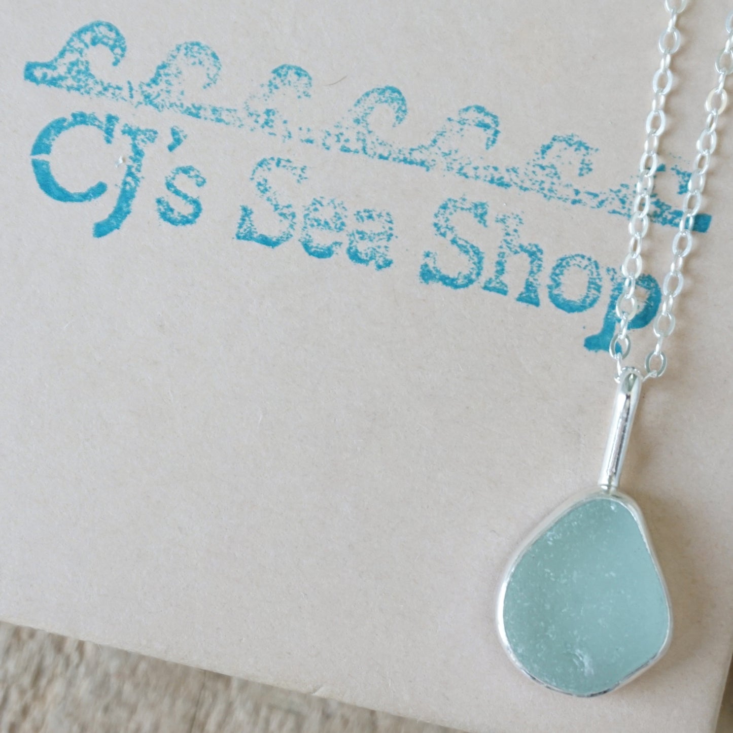 seafoam green sea glass and silver pendant, on a gift box
