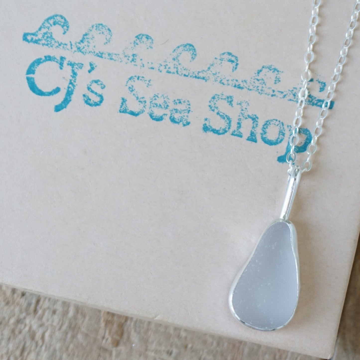 light lavender sea glass and silver pendant, on a gift box