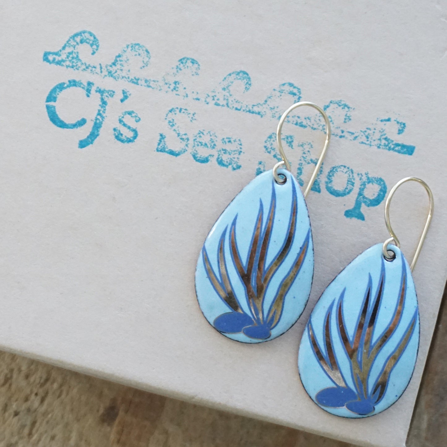 Blue and gold leaf-patterned earrings on a gift box