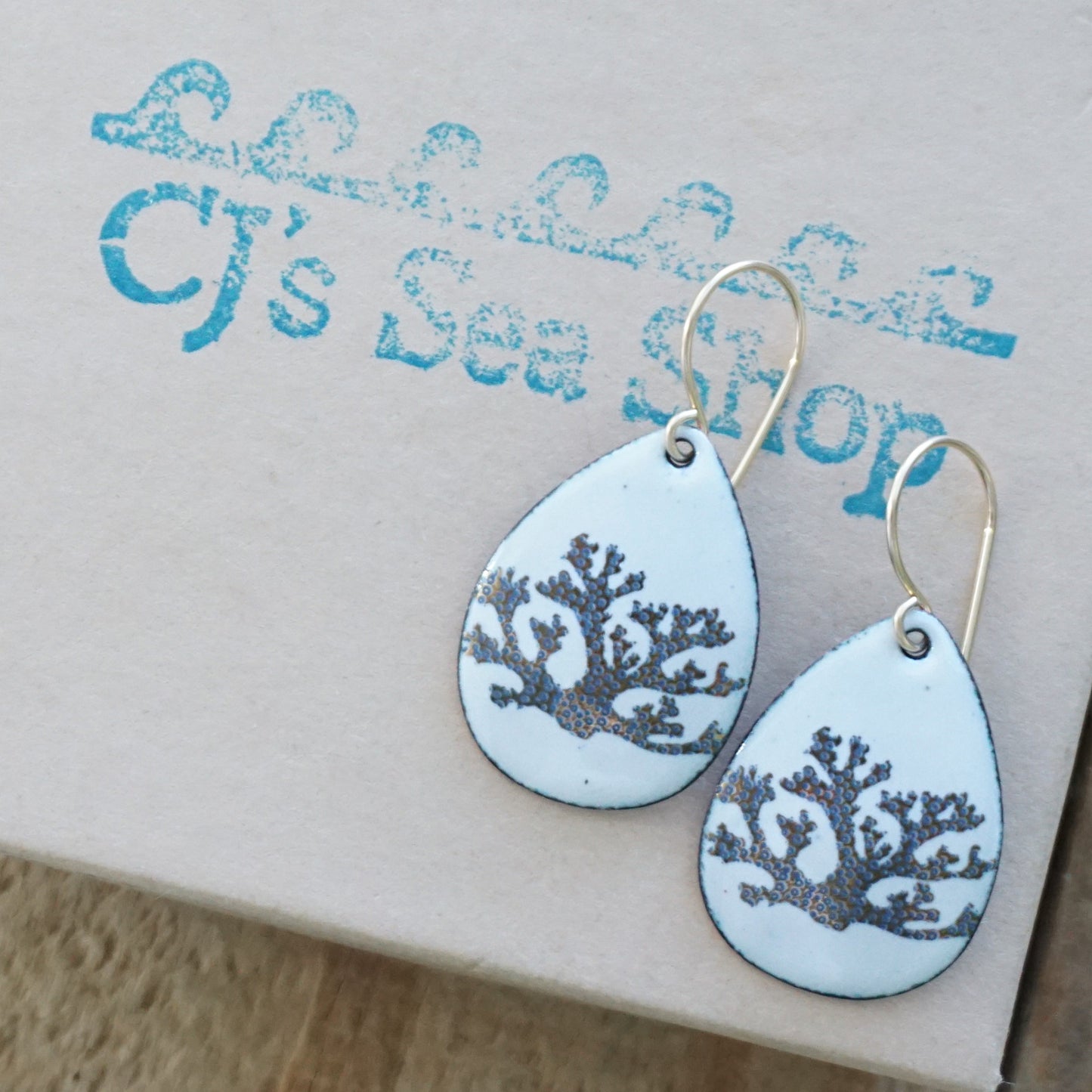 Teardrop-shaped earrings with coral design on a gift box