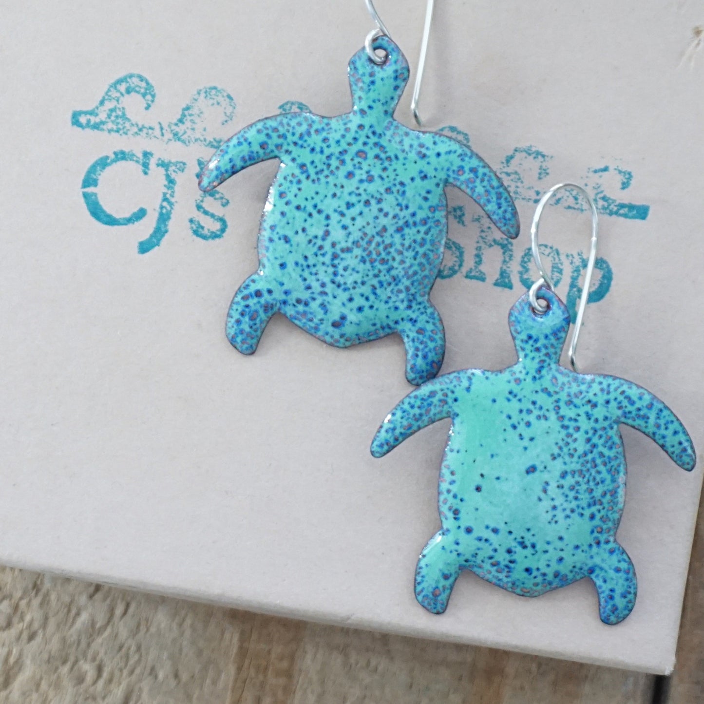 Green turtle-shaped earrings on a gift box