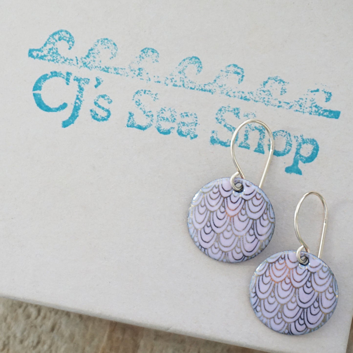 Pair of earrings with pink and gold pattern on a gift box