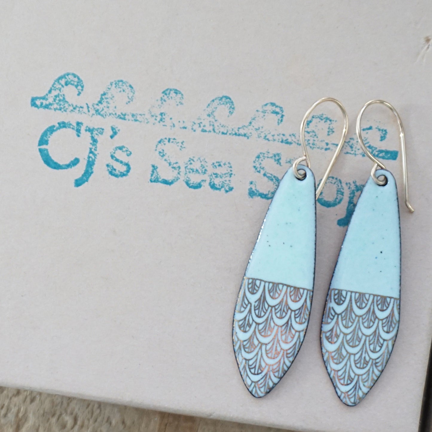 Green and gold patterned earrings on a gift box