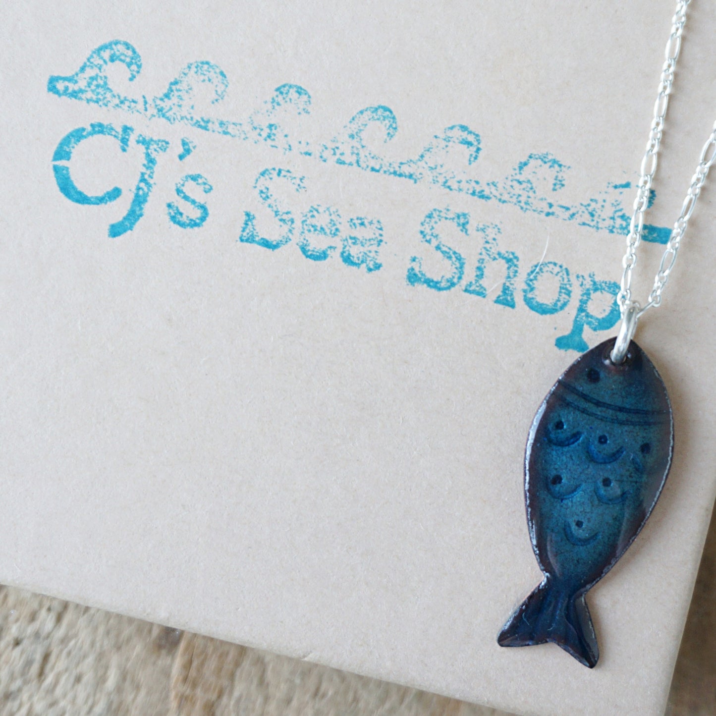 Blue fish-shaped pendant on a gift box