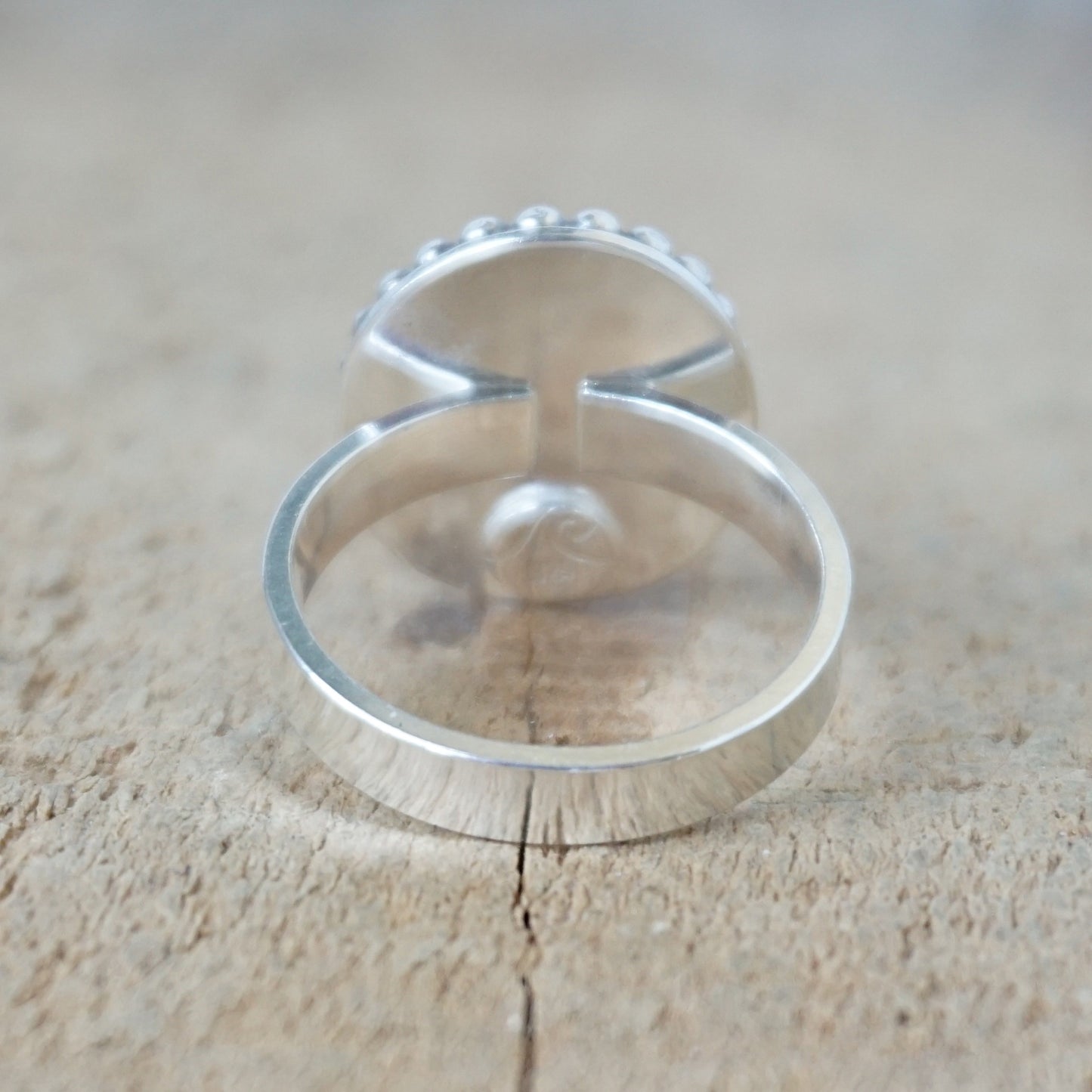 Silver ring with a turquoise stone on a wooden surface
