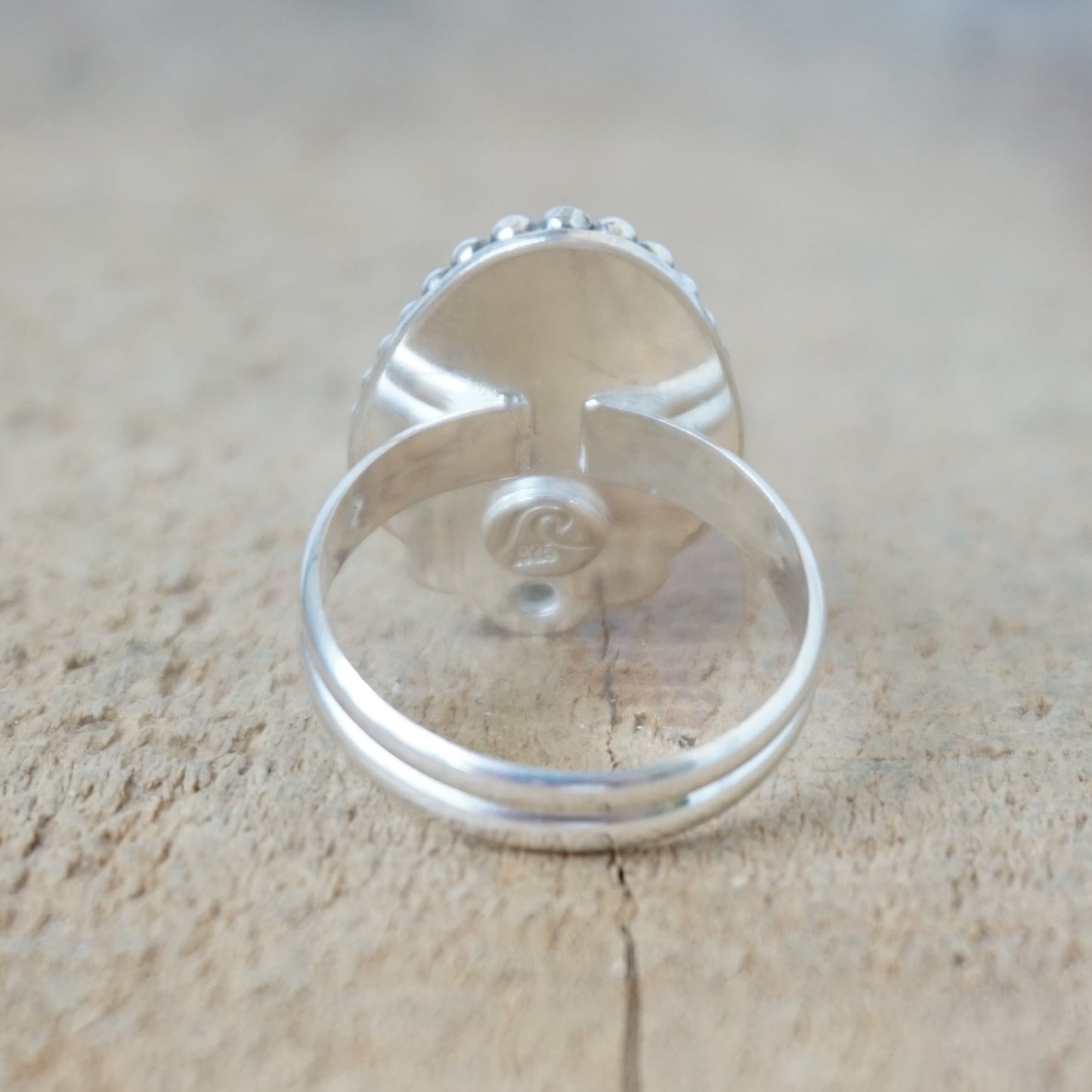 Silver ring with a turquoise stone on a wooden surface