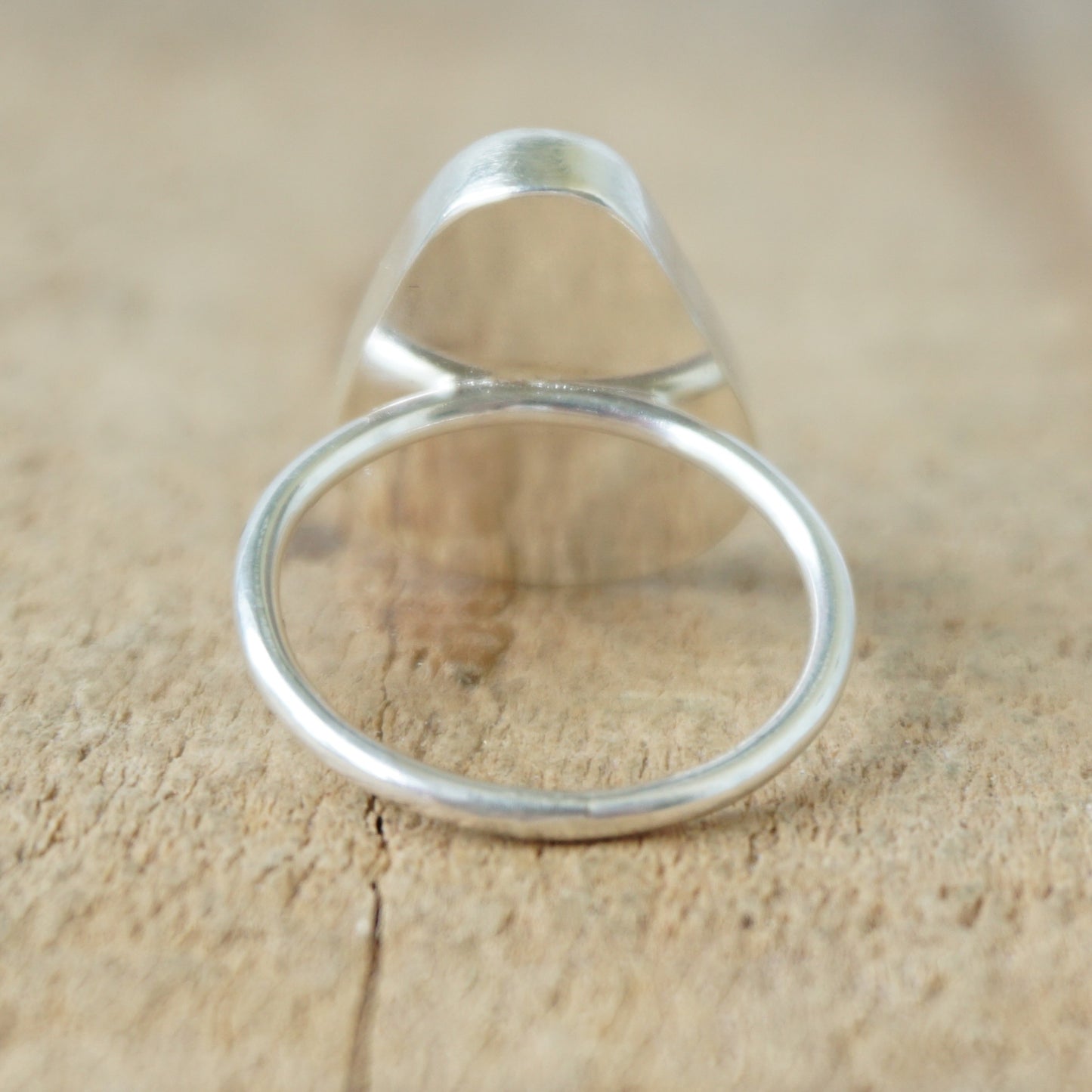 back view of a silver ring with seafoam green sea glass on a wooden background