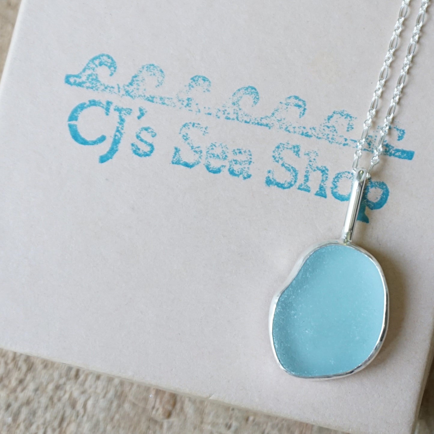 light blue sea glass pendant on a gift box