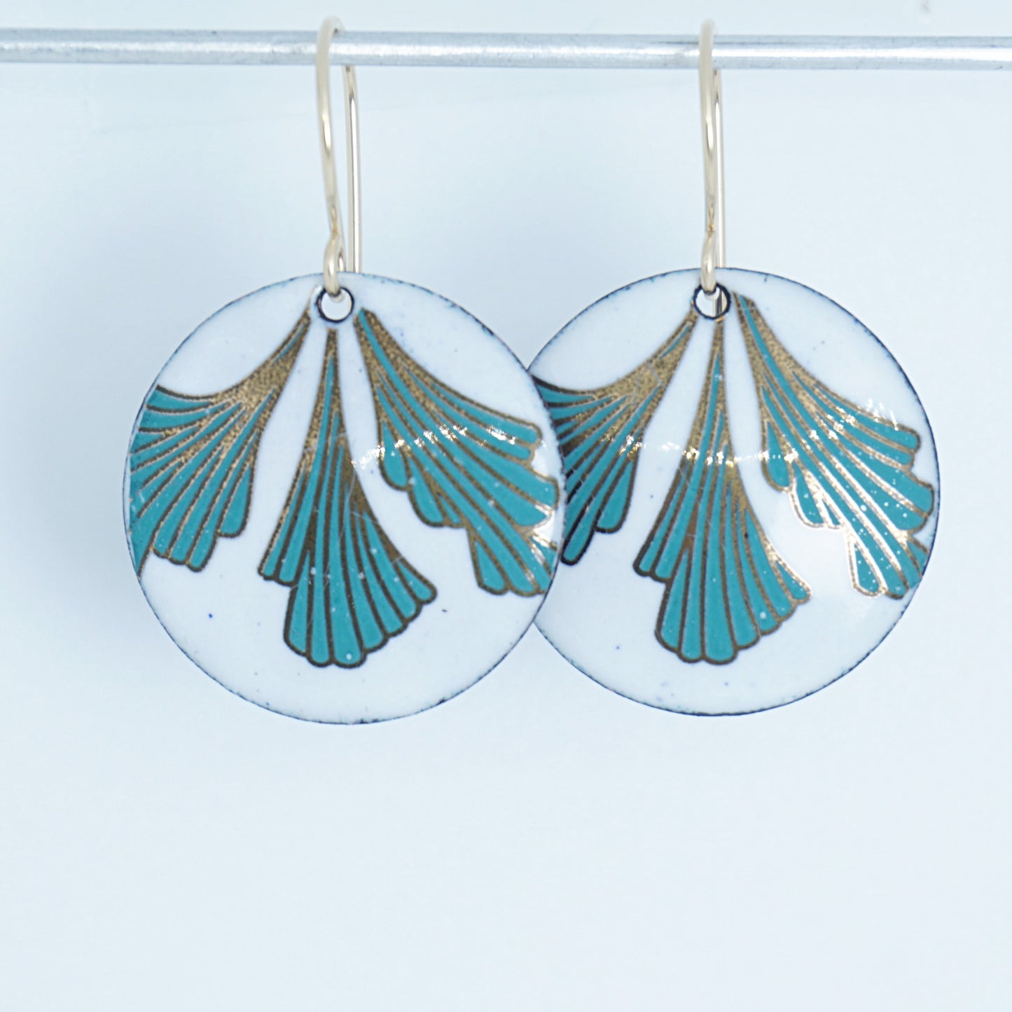 Pair of earrings with green and gold leaf-shaped designs on a white background