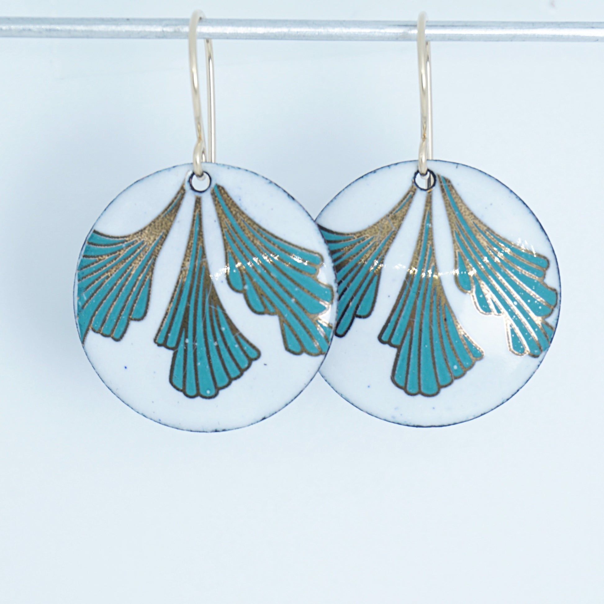 Pair of earrings with green and gold leaf-shaped designs on a white background