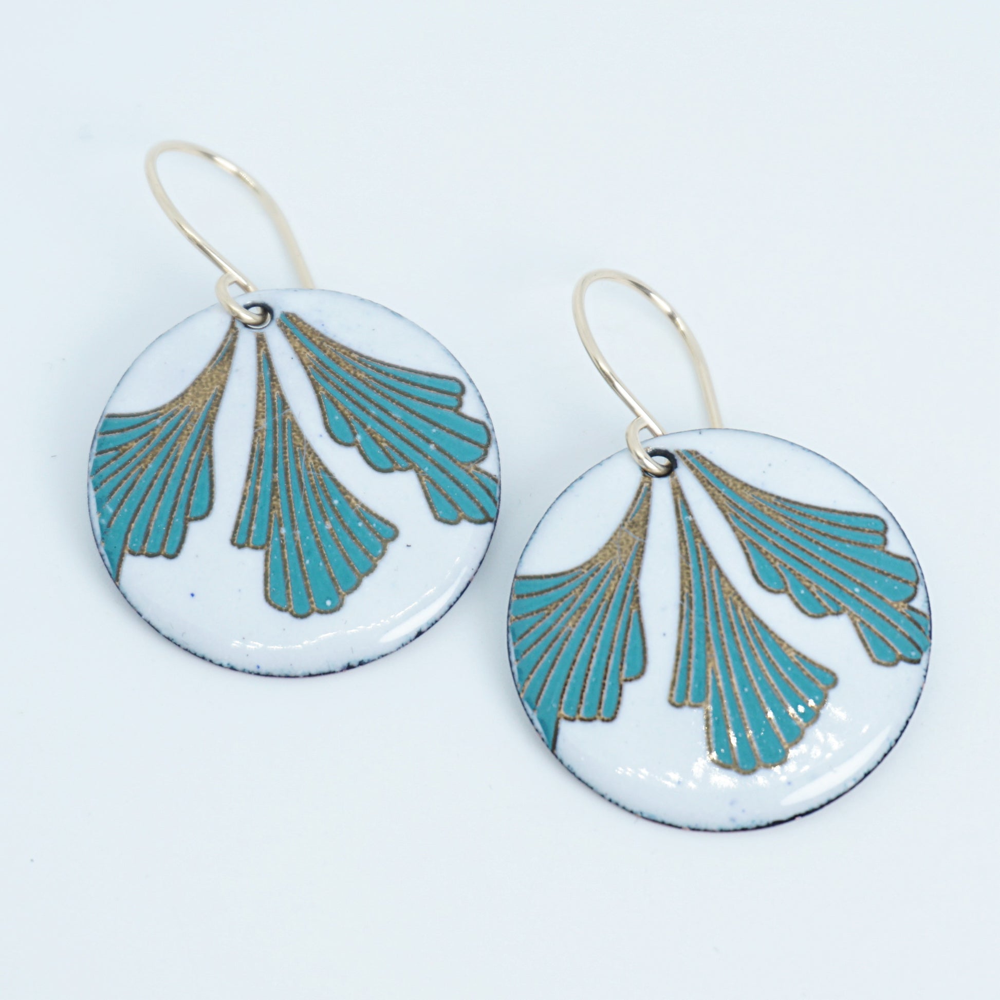 Pair of earrings with green and gold leaf design on a white background