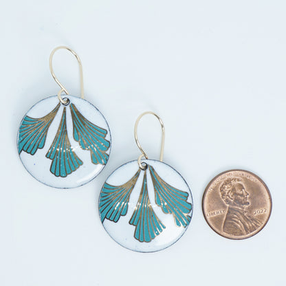Pair of earrings with green and gold design on a white background, next to a penny for scale.