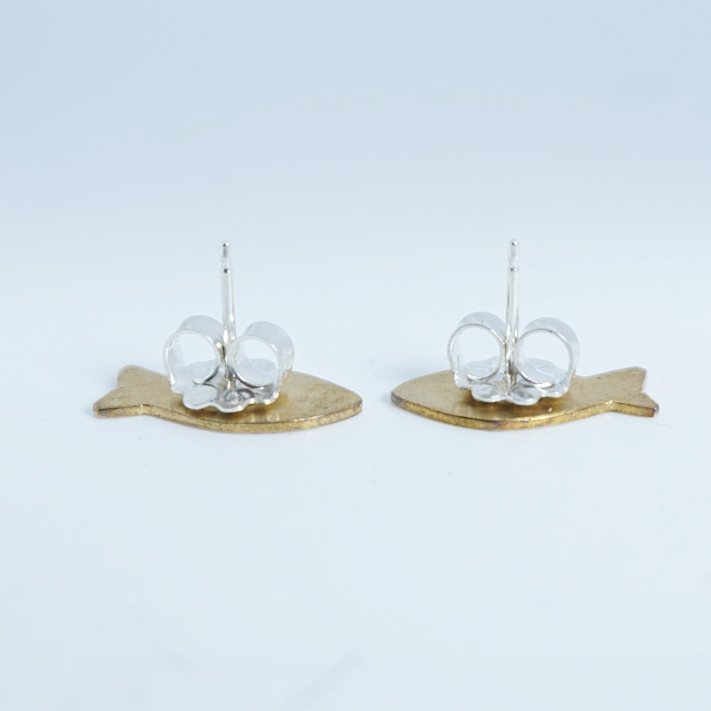 side view of a Pair of earrings with gold fish-shaped bases on a white background