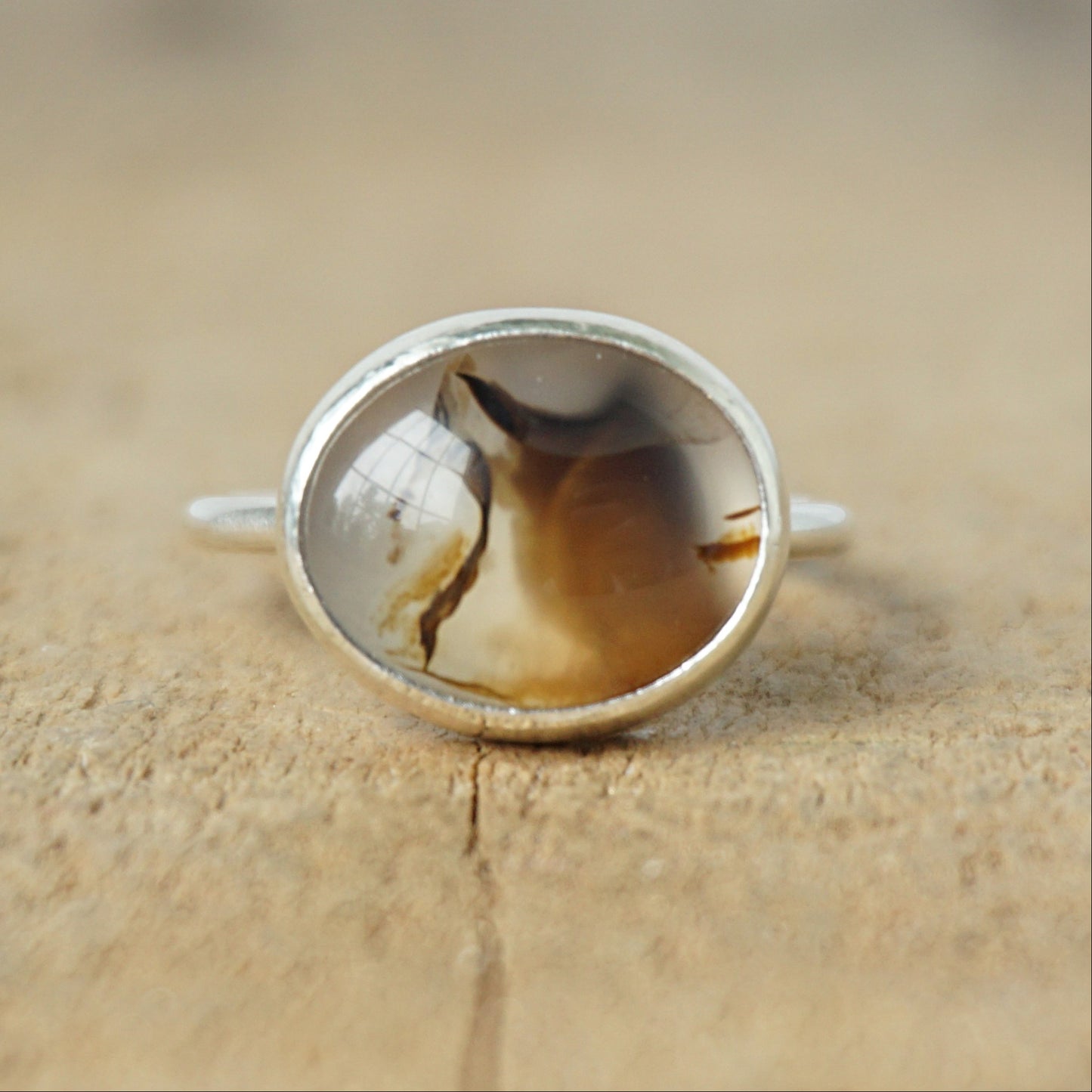 silver ring with a brown stone on a wooden background