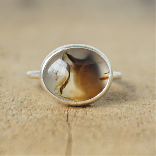 silver ring with a brown stone on a wooden background