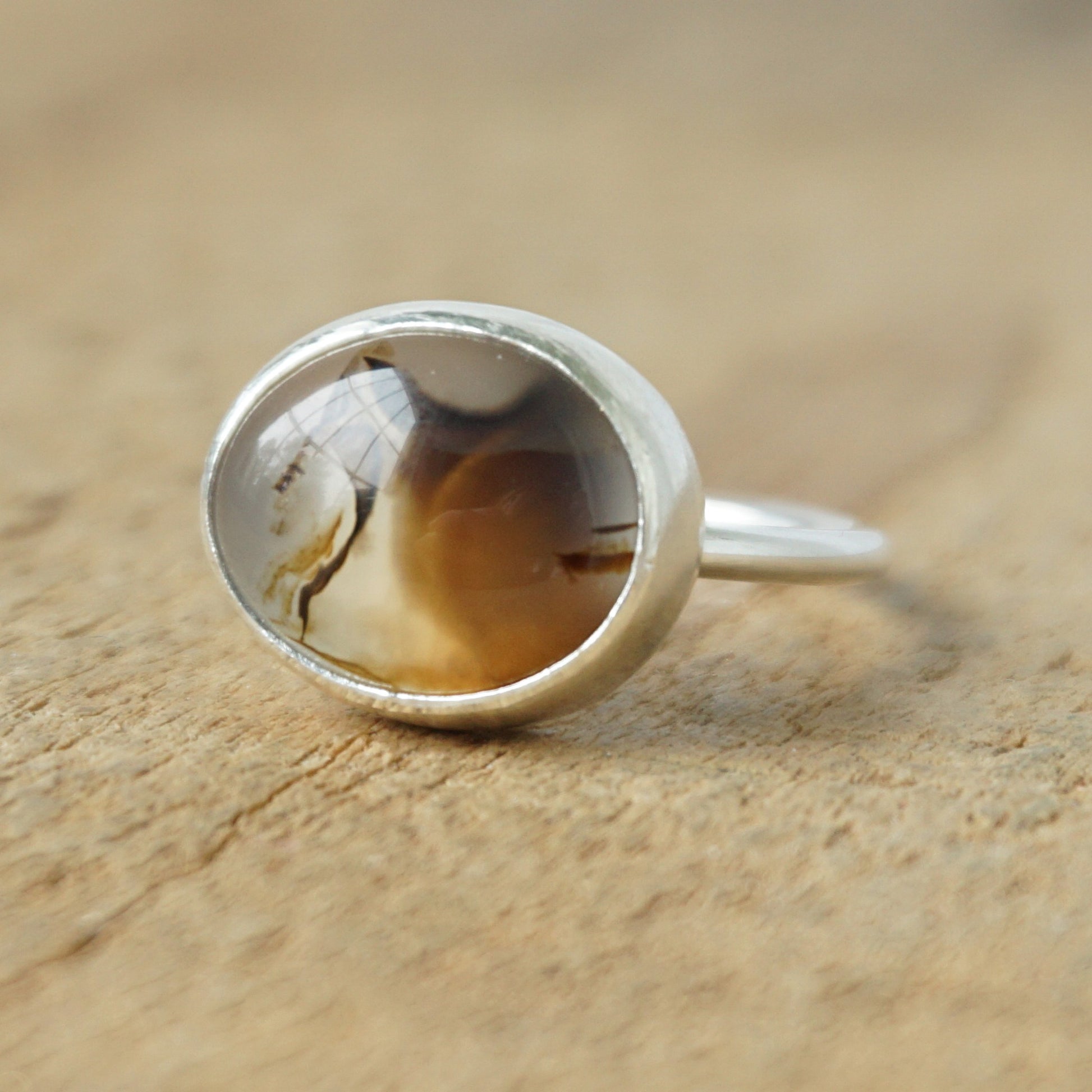 silver ring with a brown stone on a wooden background