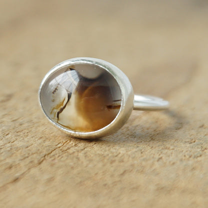 silver ring with a brown stone on a wooden background