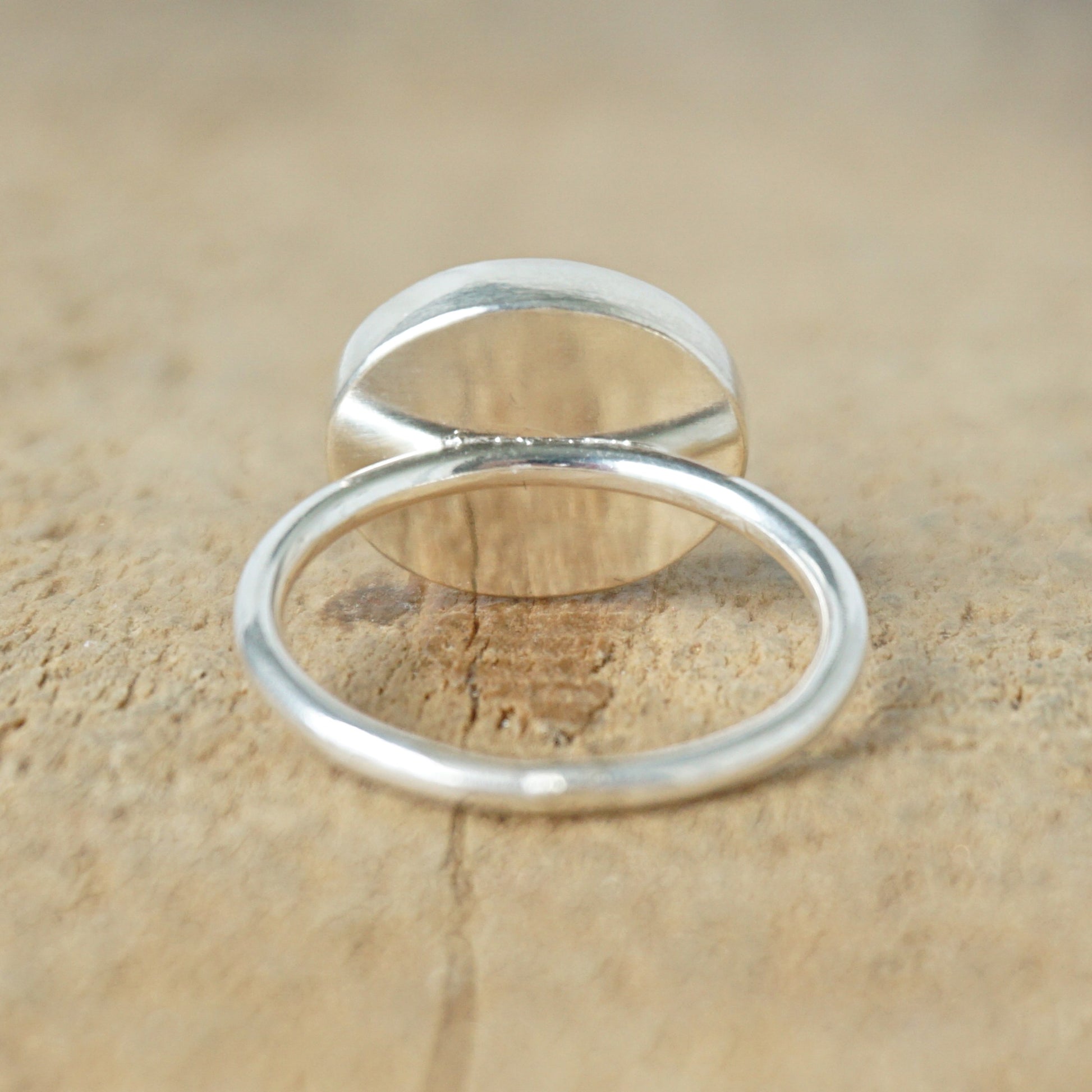 back view of a silver ring with a brown stone on a wooden background