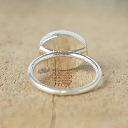 back view of a silver ring with a brown stone on a wooden background