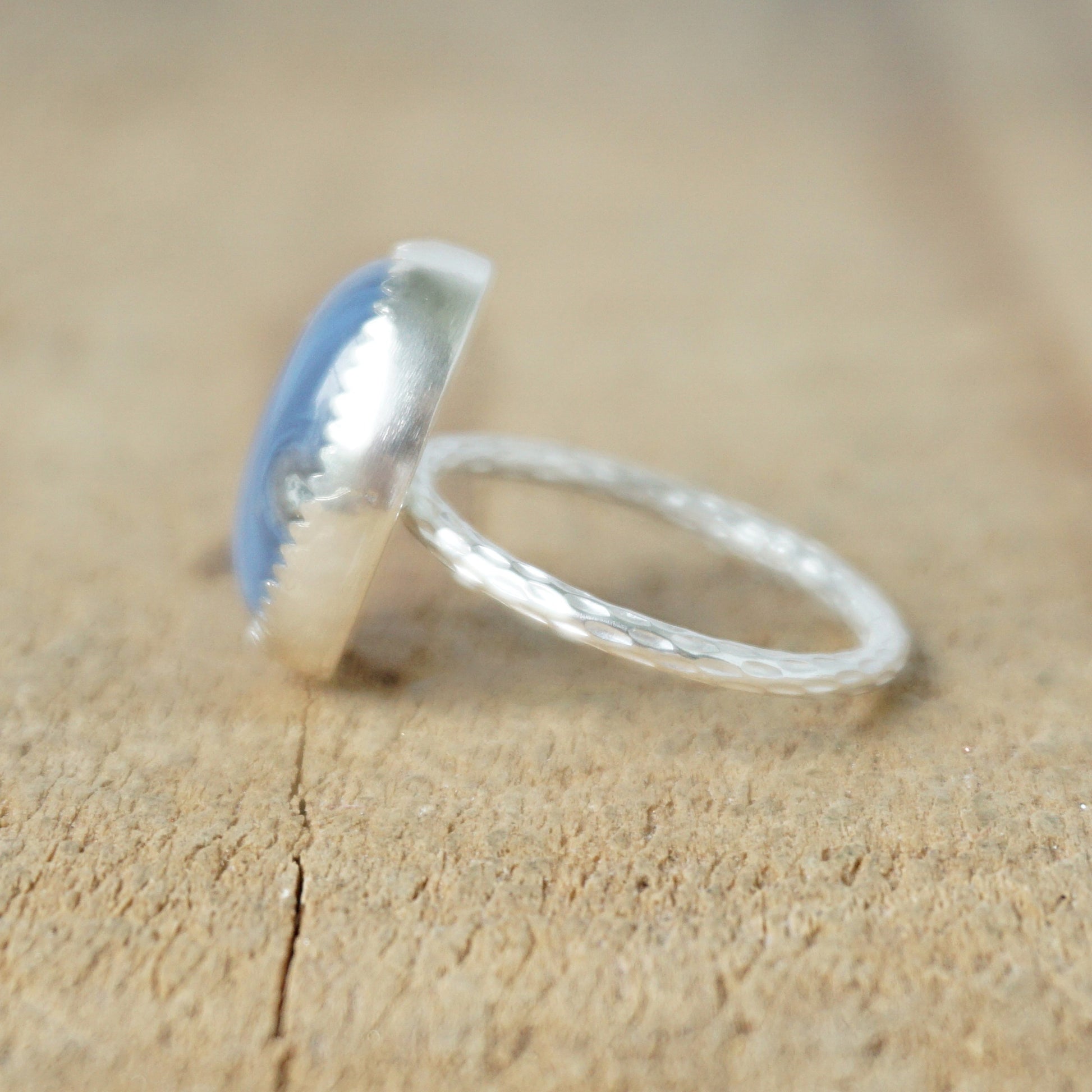 side view of a silver ring with a blue stone on a wooden background