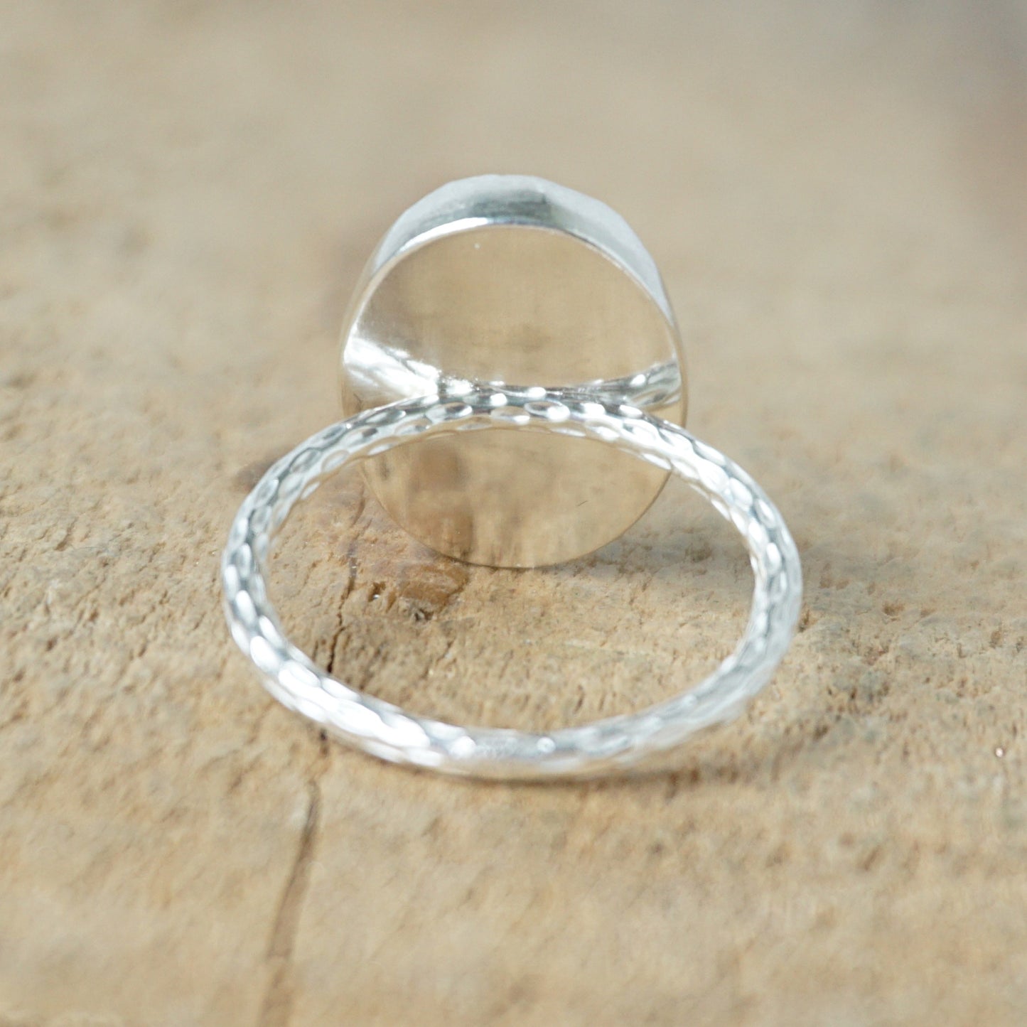 back view of a silver ring with a blue stone on a wooden background