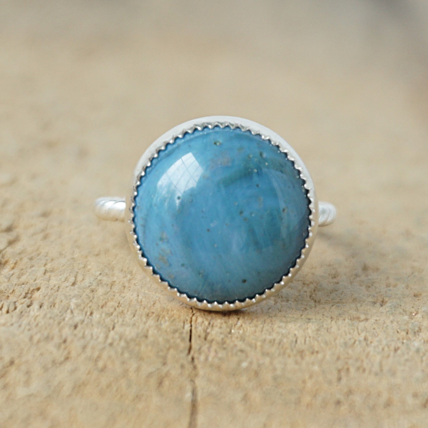 silver ring with a blue stone on a wooden background