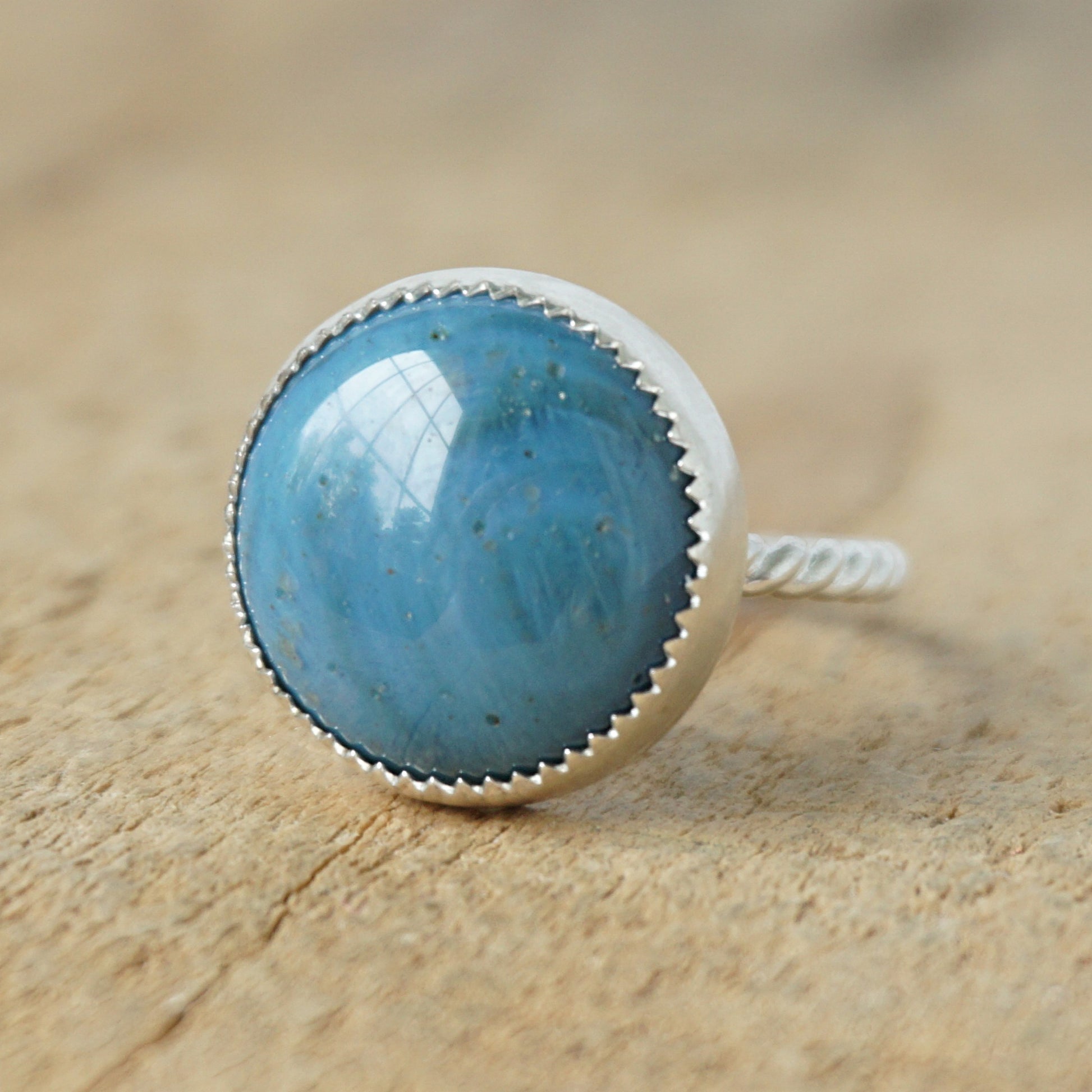 silver ring with a blue stone on a wooden background