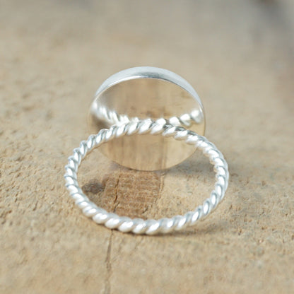 back view of a silver ring with a blue stone on a wooden background