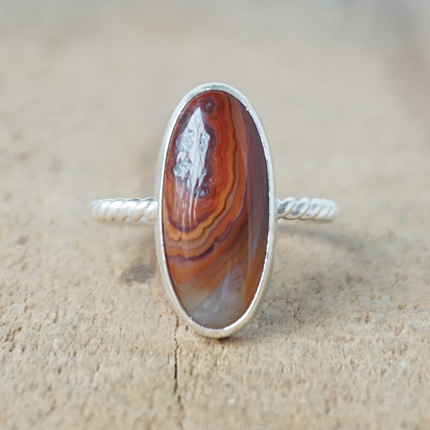 Silver ring with a brown oval stone on a wooden background