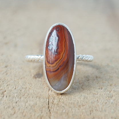 Silver ring with a brown oval stone on a wooden background