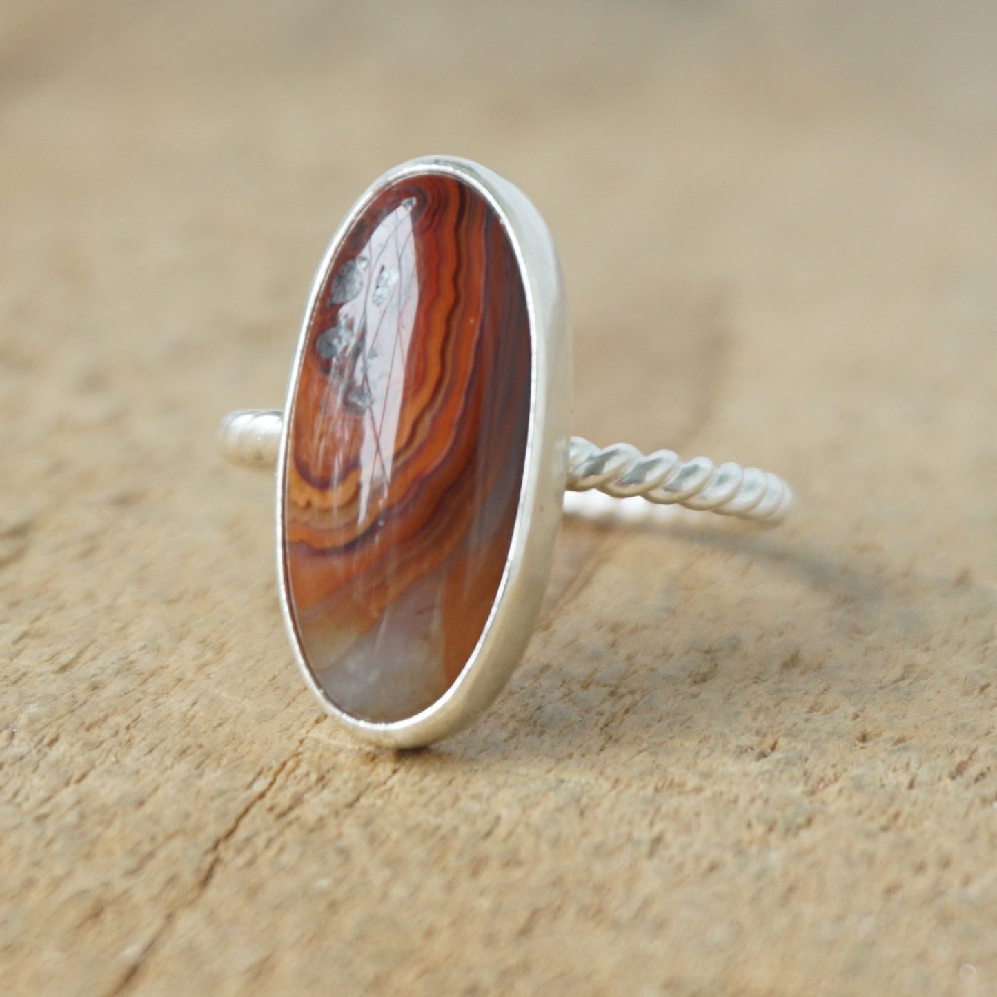 Silver ring with a brown oval stone on a wooden background