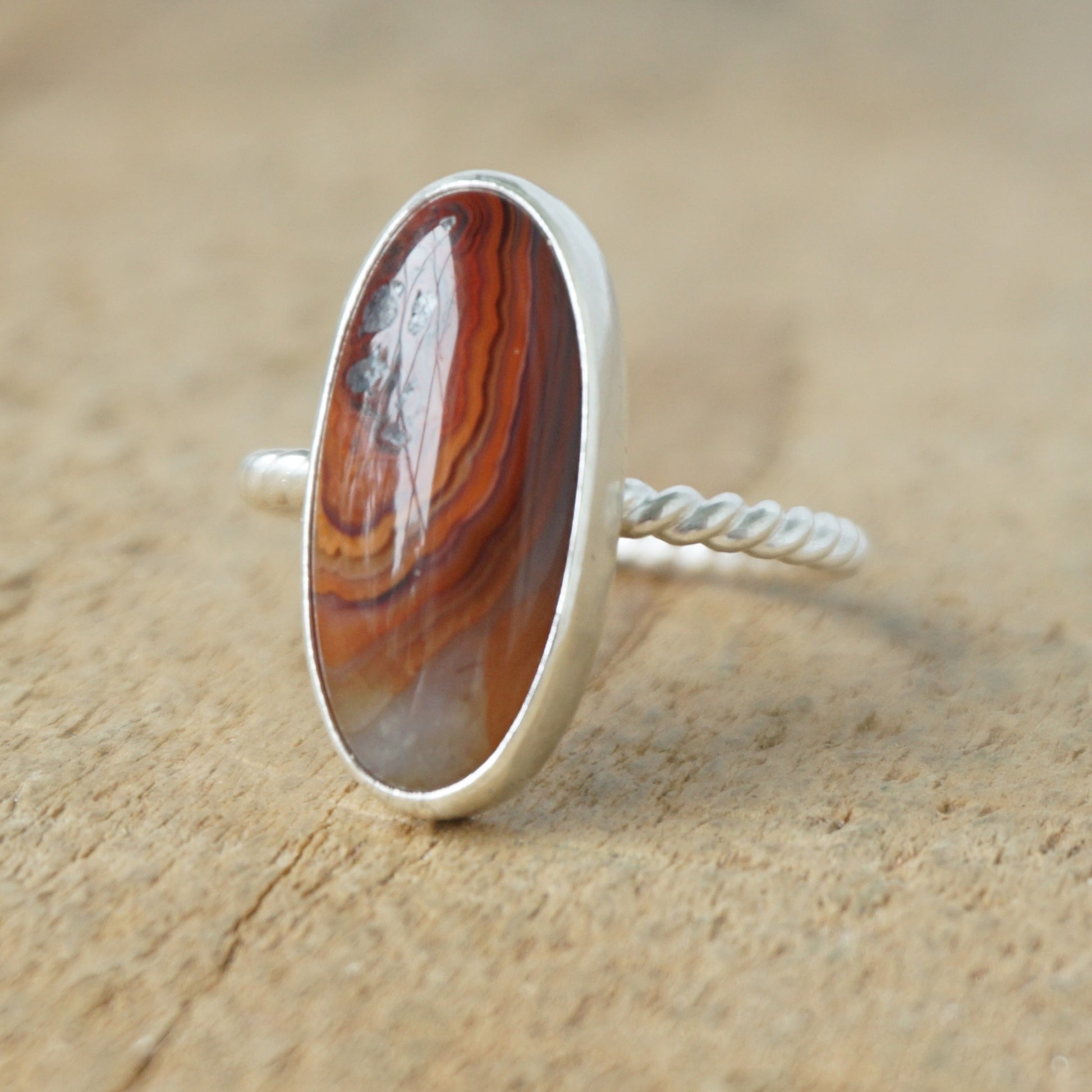 Silver ring with a brown oval stone on a wooden background