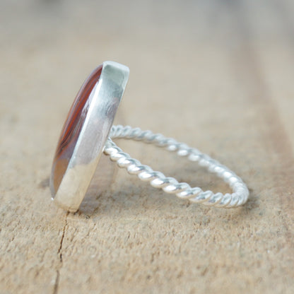 side view of a Silver ring with a brown oval stone on a wooden background