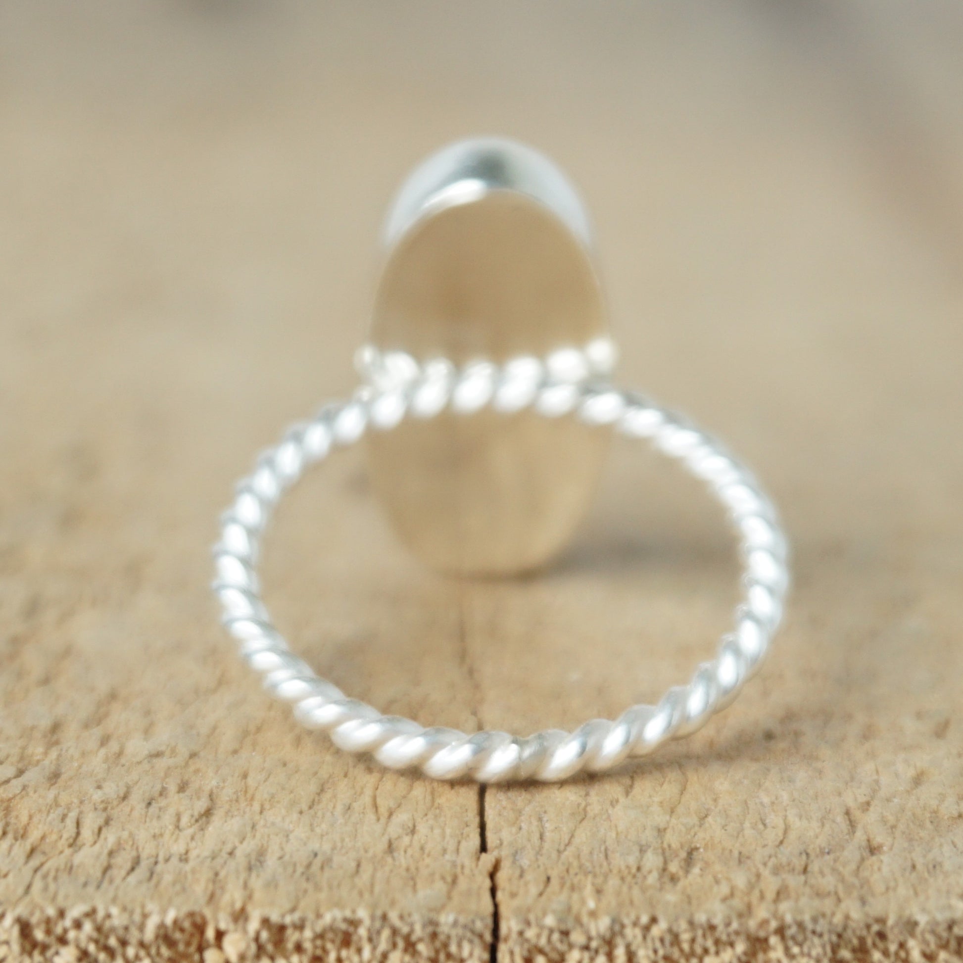 back view of a Silver ring with a brown oval stone on a wooden background