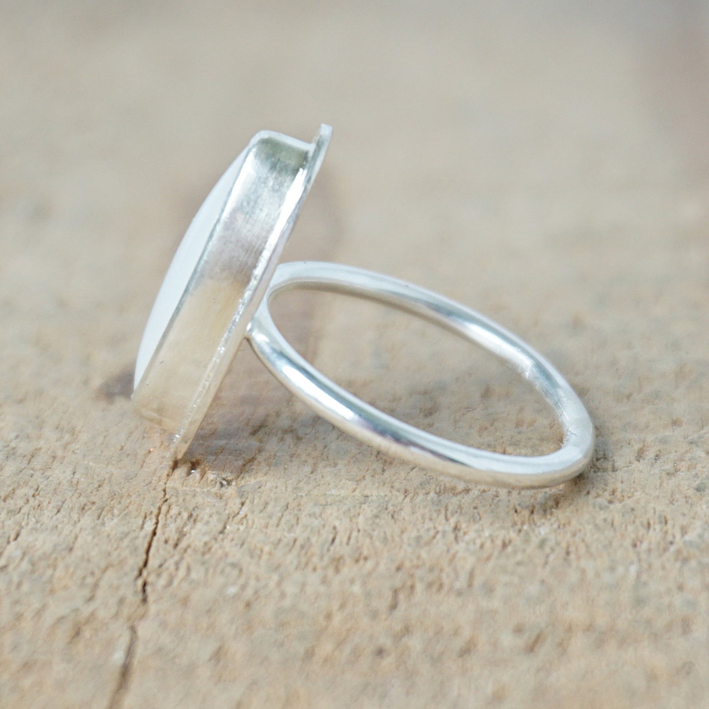 side view of a Silver ring with a white stone on a wooden surface